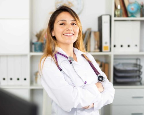 Portrait of confident latina female doctor standing in clinic office